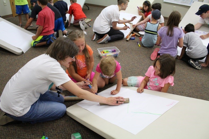 STEM kids and instructor drawing on paper