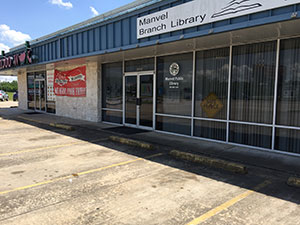 A library located in a strip shopping center location, next to a restaurant.