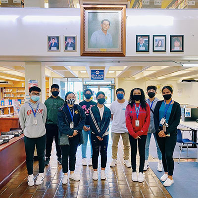 High School interns standing inside library.
