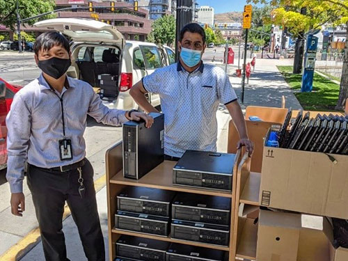 A picture containing persons standing outdoors with boxes of computer equipment.