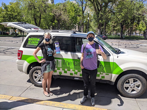 A person and person standing next to a van with a bottle of water.