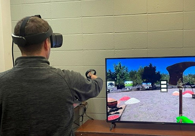 man with virtual reality headset and screen showing the VR Village