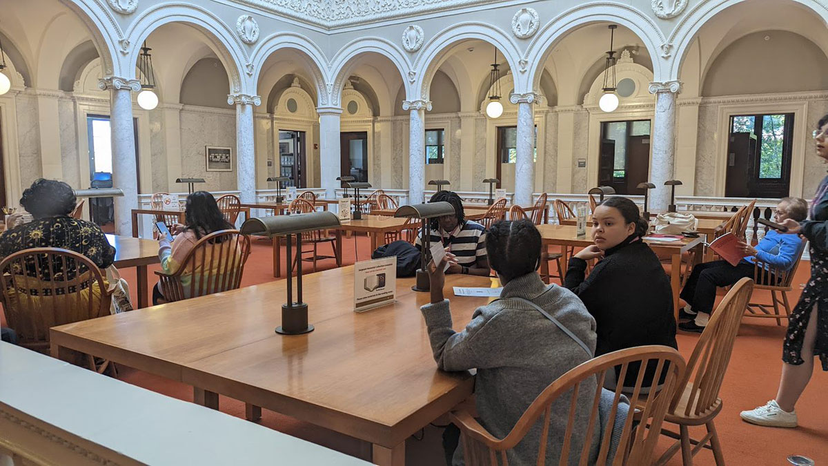 People seated at table in library hall.