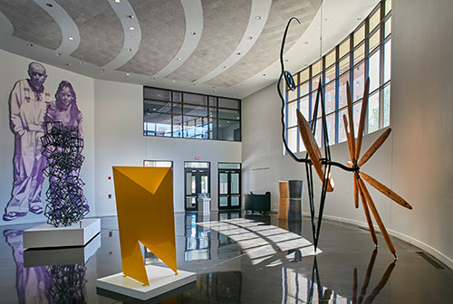 Museum lobby displaying artwork, sculptures and a wall mural.