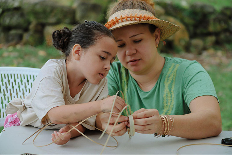 woman and child participate in Papahana Kuaola Ohana Weaving Session