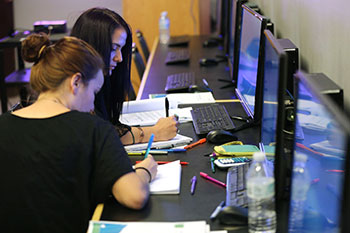 Two girls sitting at computer stations in a library.