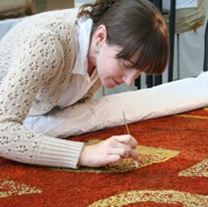 Aimee Ducey, conservation program intern from New York University, removing accretion from the sacred Hawaiian cloak.