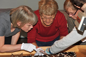 museum sewers closely examine an artifact