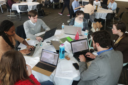 Group of students with computers sitting at table.