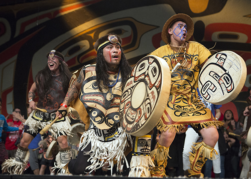 Three male Git Hoan dancers in traditional regalia performing in celebration 2016