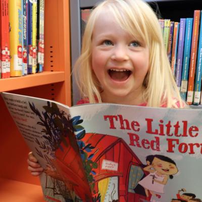Little girl reading book in library