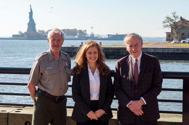 Three people standing for photo, Statue of Liberty in the background