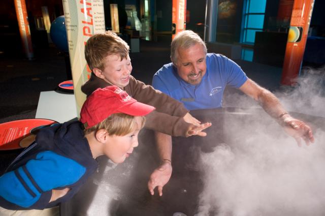 Museum volunteer and two young visitors explore the mysteries clouds.