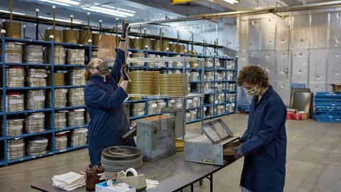 Film archivists recanning and cleaning Pakistani films. Shelving units in background hold processed Indian films. Photo courtesy of The George Eastman Museum.