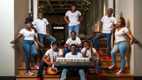 A group of gifted and talented teenagers, dressed in blue jeans and white shirts, pose with musical instruments on stage at the The B.B. King Museum and Delta Interpretive Center.  