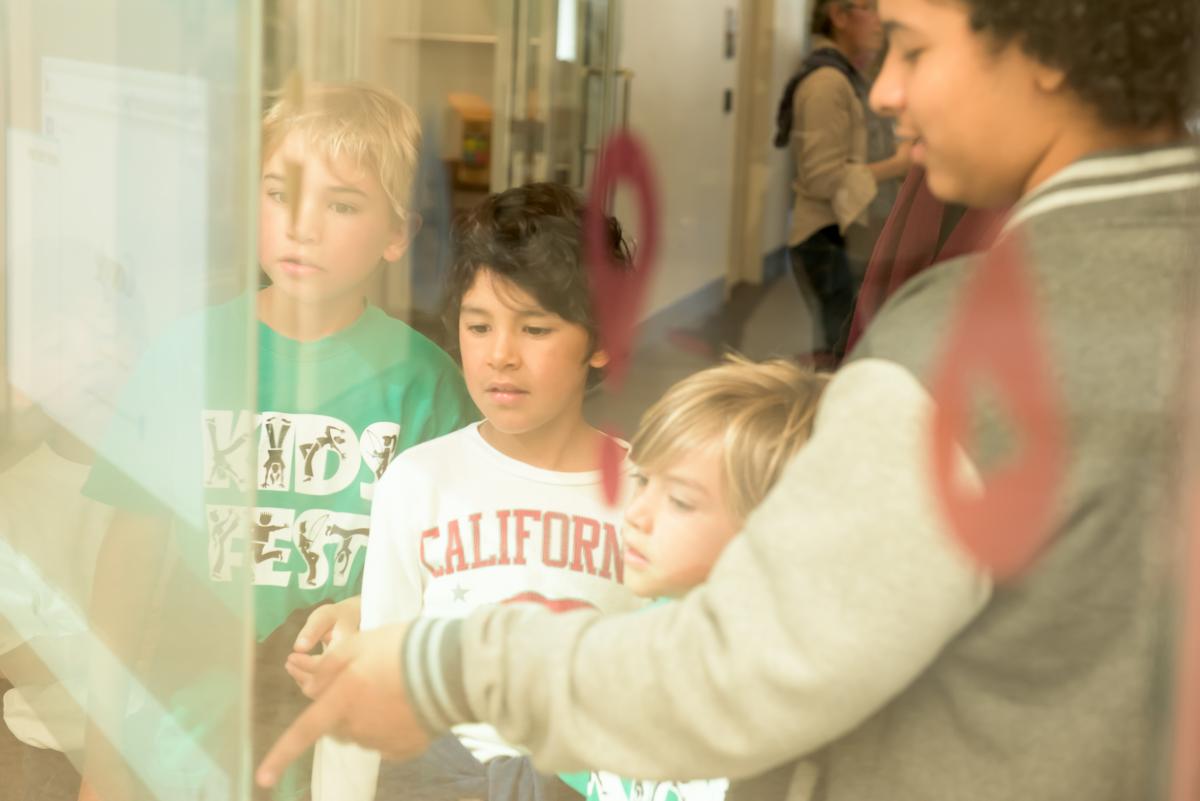 A teenager leads a demonstration for younger children at the San Francisco Public Library